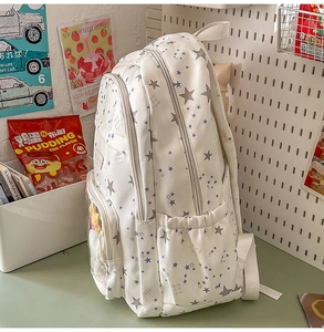 Close-up of white school backpack with star prints and multi-pocket storage detail