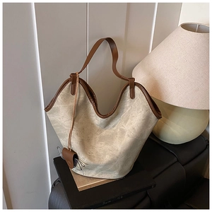 Detail of vintage beige tote bag with brown leather trim and matching charm pendant