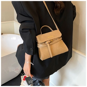 Detail of a brown matte leather crossbody bag featuring gold MYBAOB logo and buckle strap