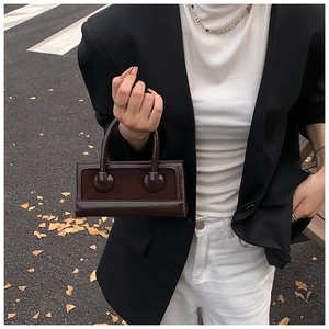 Detail of dark brown vintage handbag featuring contrast textures and short top handle