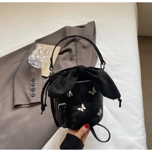 Detail of black patent leather bucket bag with silver butterflies and drawstring bow closure
