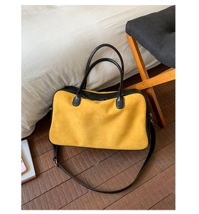 Detail of yellow matte suede tote bag with black leather accents and adjustable strap