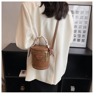 Détail du sac seau en cuir marron avec poignée en foulard et fermeture éclair dorée