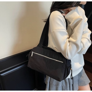 Side view of black nylon shoulder bag with silver zipper and drawstring detail shown on model