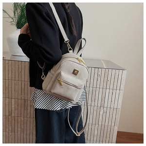 Macro view of light gray faux suede mini backpack with gold hardware and logo detail