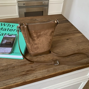 Detail of a brown suede and leather bucket bag showing dual-material texture and stitching