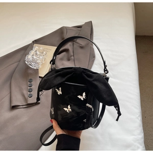 Detail of black bucket bag with silver metal butterfly and large satin bow closure