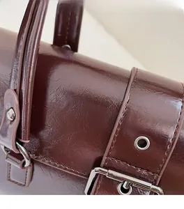 Close-up of deep red vintage leather bag showing texture, stitching and metal buckle
