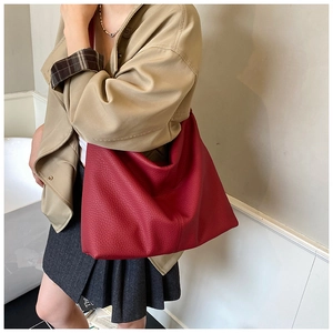 Detail of red pebbled leather hobo tote showing vertical stitching and soft texture