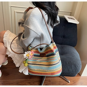 Detail der bunt gestreiften geflochtenen Strandtasche mit Lederriemen und Blumenanhänger
