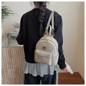 Rear view of a light beige mini backpack featuring gold zippers and premium leather texture