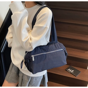Detail of navy blue nylon shoulder bag featuring silver metal zipper and drawstring side