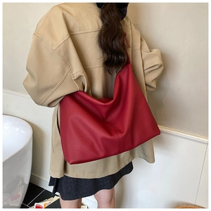 Red hobo shoulder bag with litchi grain texture worn by a model in casual attire