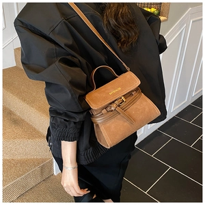 Detail of a brown frosted texture handbag with gold MYBAOB logo and buckle decoration