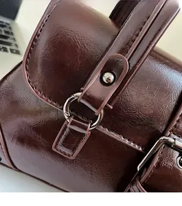 Detailed close-up of dark brown oil wax leather bag with polished silver hardware rings