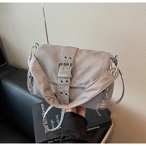 Détail du sac bandoulière en nylon gris avec grande boucle à œillets et poche latérale zippée