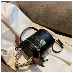 Détail du sac seau en cuir noir avec foulard en soie léopard et finitions dorées chic