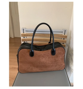 Close-up of brown suede tote bag featuring black leather trim and double zipper closure