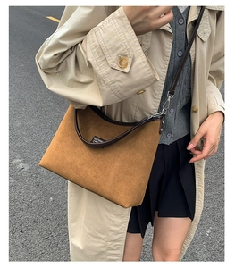 Close-up of vintage brown suede shoulder bag with premium leather trim on model
