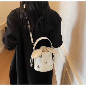 Detail of white bucket bag with colorful butterfly embroidery and cute bunny ear drawstring