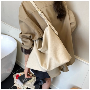 Detailed view of cream-colored pebble leather tote bag with adjustable shoulder strap