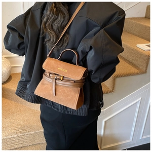 Brown matte retro small square bag with top handle shown on model's shoulder