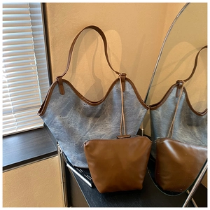 Detail of blue denim tote bag with brown leather trim and matching inner pouch