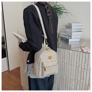 Detail view of a beige mini PU leather backpack with gold hardware and multi-pocket design