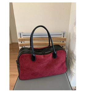 Detail of burgundy suede tote with black faux leather handles and zipper closure