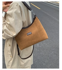 Close-up of brown matte suede shoulder bag with contrast piping and silver hardware