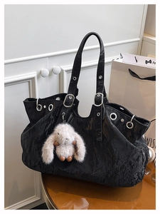 Dettaglio della borsa tote nera stropicciata con occhielli in metallo e charm a coniglietto