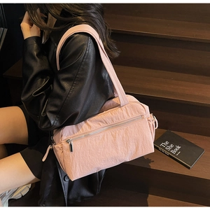 Pink nylon shoulder bag with pleated texture and silver zipper detail in a lifestyle setting