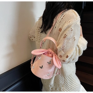 Pink bucket bag with silver butterfly charms and rabbit ear drawstring closure details