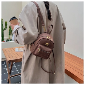 Detail of vintage dark brown faux leather backpack with gold zippers and adjustable strap