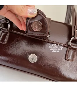 Close-up of magnetic buckle closure on dark brown faux leather shoulder bag