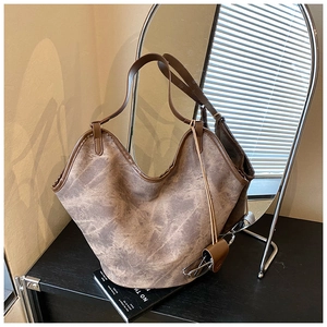 Close-up of a vintage tan faux leather hobo bag with worn texture and sturdy shoulder strap