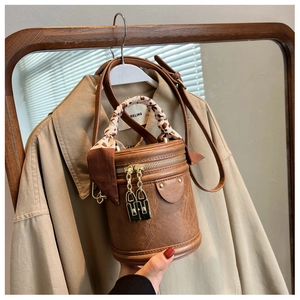 Détail du sac cylindrique marron vintage avec poignée en foulard léopard et zips dorés