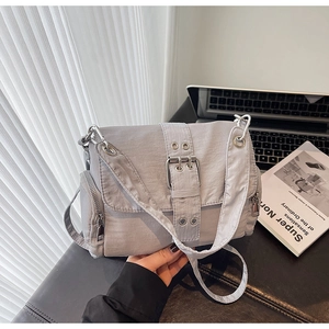 Détail du sac bandoulière en nylon gris clair avec œillets métalliques et zips latéraux