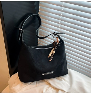 Detail of black suede dumpling bag with decorative wooden beads and fashion metal plate