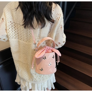 Detail of pink bucket bag featuring silver butterfly ornament and rabbit ear drawstring