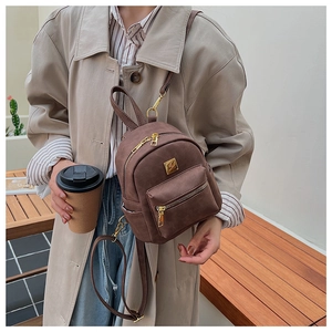 Close-up of a vintage dark brown mini backpack with golden zippers and matte texture detail
