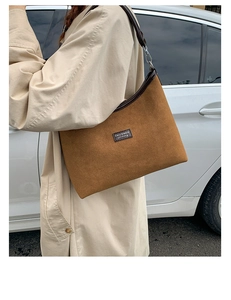 Detail of brown suede shoulder bag with leather trim and metallic adjustable buckle