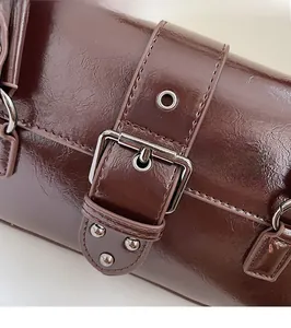 Detailed close-up of dark brown glossy leather texture with a silver buckle on the shoulder bag