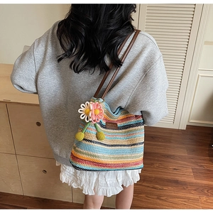 Detail der bunt gestreiften gewebten Beuteltasche mit Lederriemen und Gänseblümchen-Anhänger