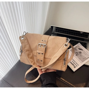 Détail du sac en toile kaki avec une grande boucle en métal et poches zippées latérales