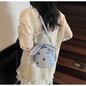 Detail of light blue bucket bag with silver butterfly charms and drawstring bow