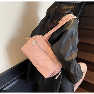 Pink pleated nylon shoulder bag with drawstring detail and wide strap worn by a model