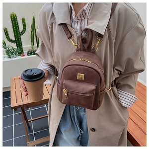 Detail of dark brown mini backpack with golden hardware and versatile strap design