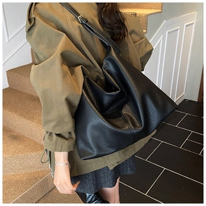 Detail of black pebbled leather hobo bag with wide strap and metallic buckle