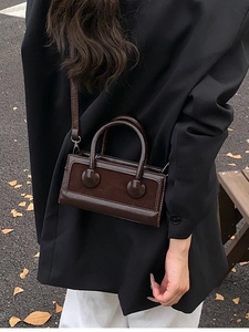 Chic dark brown square handbag with twin handles and strap in autumn outdoor setting
